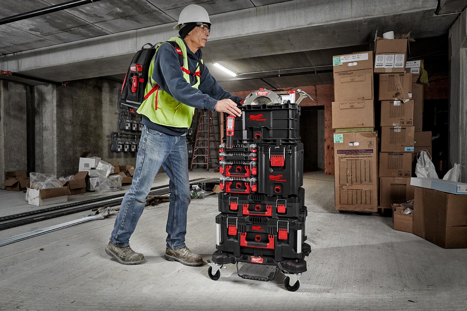 Pracovník tlačiaci Milwaukee PACKOUT vozík zložený z rôznych modulov.